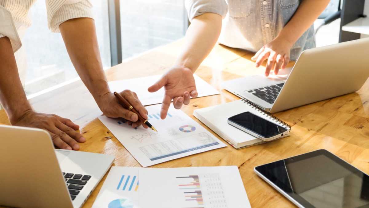 Equipe revisando documento e aprovando informações em mesa de trabalho