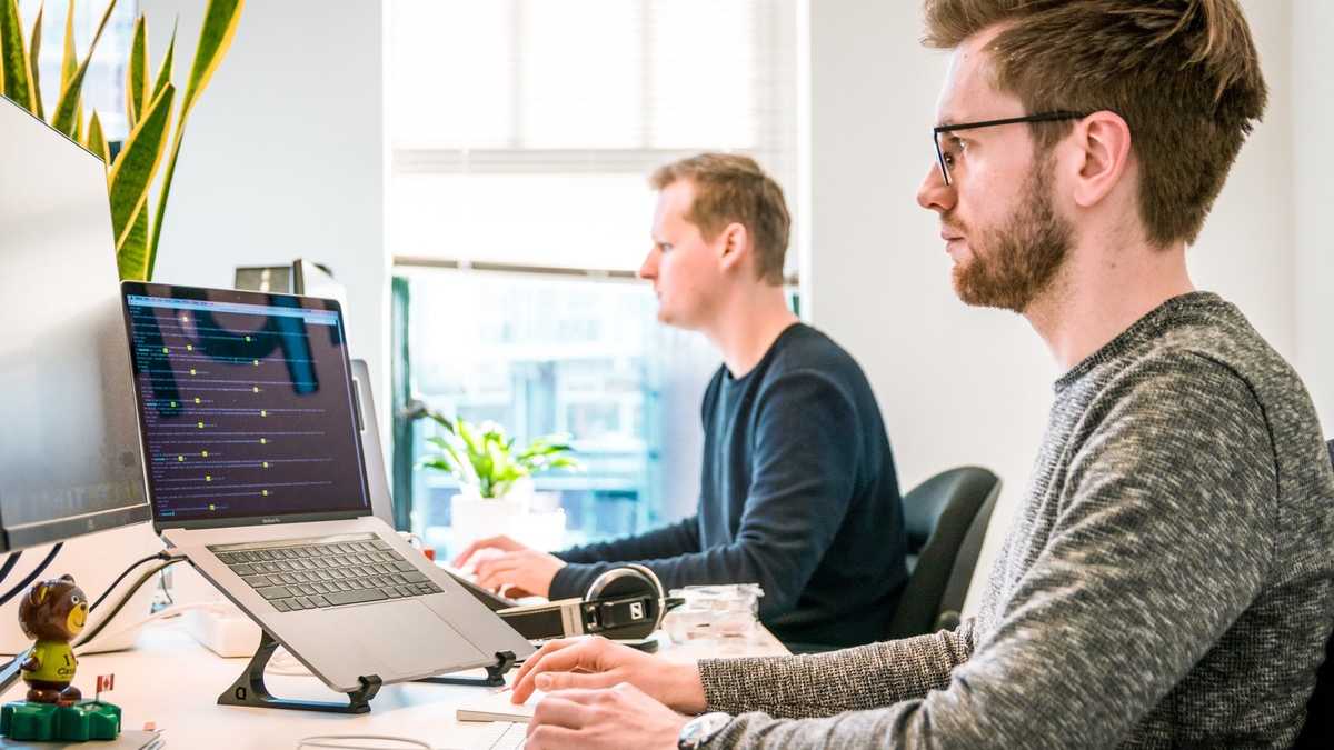 Equipe revisando telas e fluxos em estações de trabalho antes da aprovação
